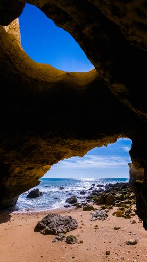 A vertical shot of a beautiful seascape seen from a cave located on the shore of a beach