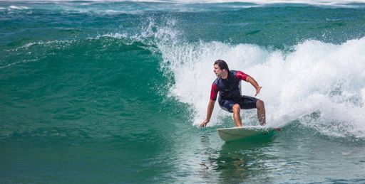 A handsome male surfer catching the wave at the sea