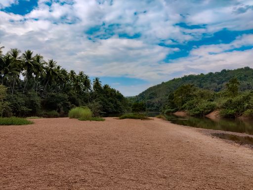 A beautiful landscape with a flowing river surrounded by greens gleaming under the cloudy sky