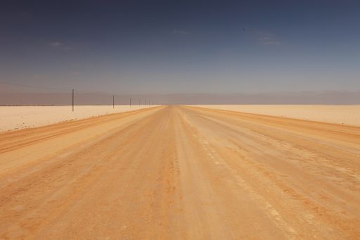 A long shot of a desert sand highway with power lines at the side