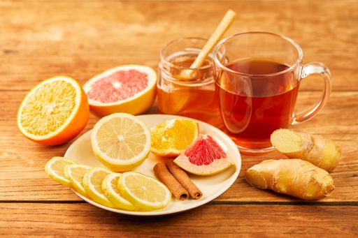 Fresh citrus, cinnamon, ginger, honey and a cup of hot tea on a wooden table