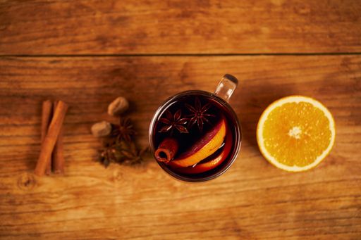 A top view of a cup of tea with citrus and cinnamon on a wooden table