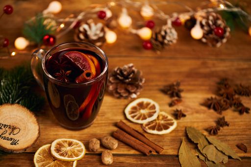A cup of hot tea with citrus and cinnamon on wooden table with dried lemon slices and Christmas decors