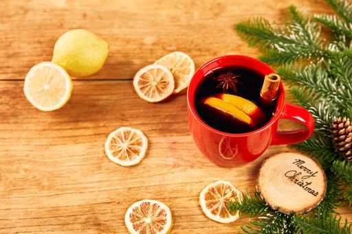 A mug of mulled wine with cinnamon sticks and orange on a wooden table