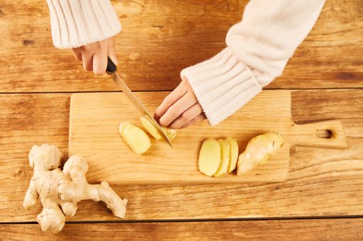 A female cutting a ginger on a chopping board