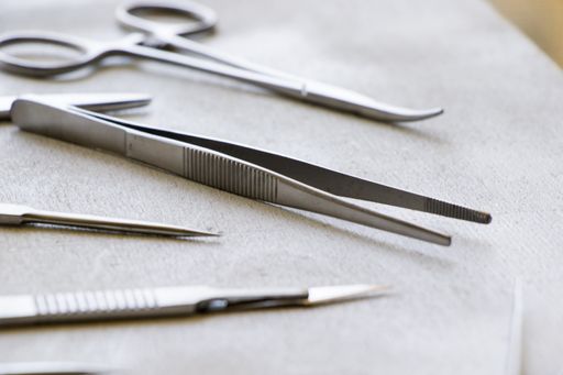 A selective focus shot of medical tweezers with other dissecting kits on wooden table