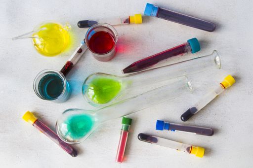 A top view of colorful chemicals in tubes and beakers on the table in a laboratory