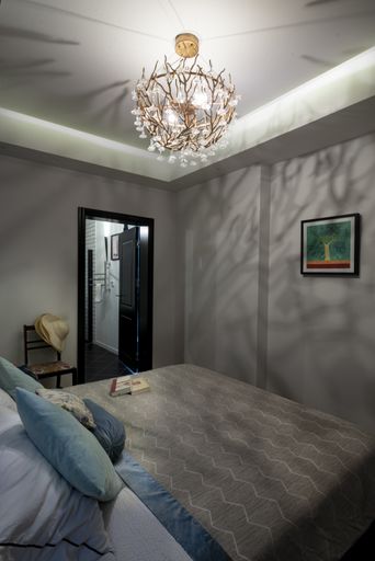 A vertical shot of a sleeping room interior with a bed and picture on the wall