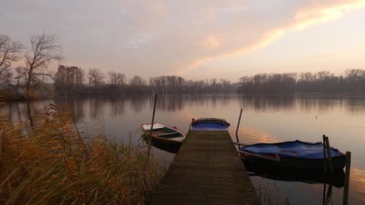 The small boats by a wooden pier in a lake captured during sunset