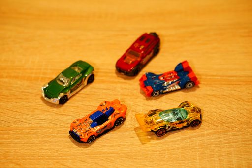 Mattel Hot Wheels race toy model cars on a wooden table in soft focus