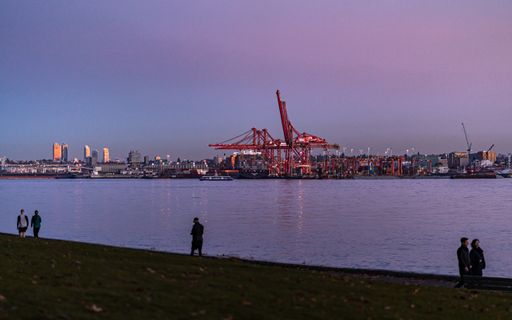 A beautiful purple twilight sunset over the Vancouver container port by the water. Across the water is Stantley Park as pedestrians enjoy a nice walk.