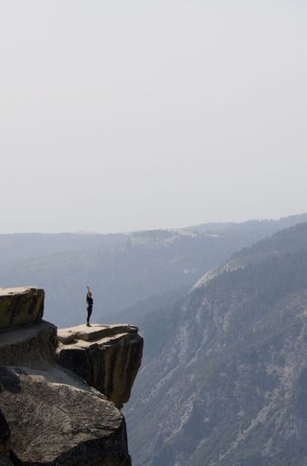 A vertical shot of a man standing on the edge of a rock