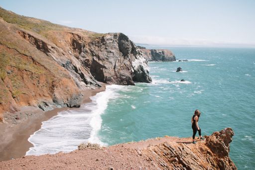 A high-angle view of a young girl standing on the edge of a rock