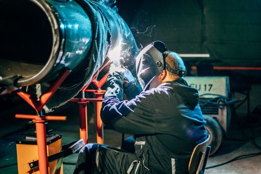 A shallow focus of a welder wearing a protective helmet and welding steel in a factory