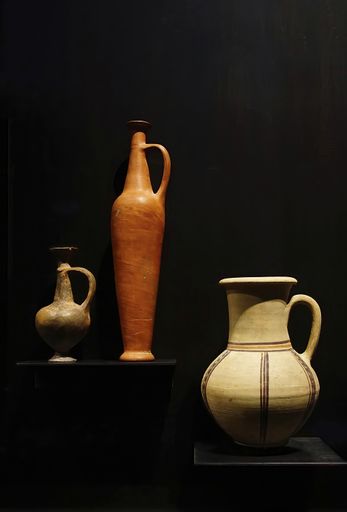 A vertical shot of jars & pottery vases from ancient Egypt, on a black background