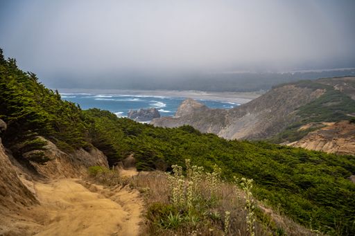 A scenic view of the vast expanse of the ocean from the edge of a cliff, with a rocky outcropping providing a stunning natural overlook