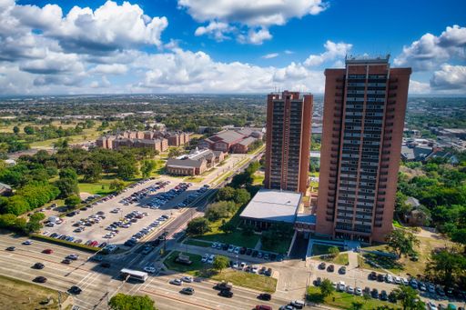 A beautiful view of apartment buildings and parked cars under the blue cloudy sky