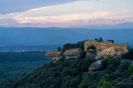 A mesmerizing shot of ruins of an old fortress in a mountainous area under the cloudy sk