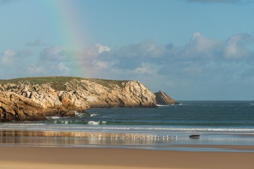 Baleal beach with atlantic ocean and rainbow in the sky and seagulls on the sand in Peniche, Portugal