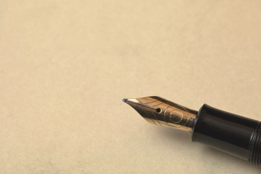 A closeup of a fountain pen on the table under the lights with space for tex