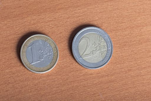A top view shot of two gold and silver euro coins on a wooden table surface
