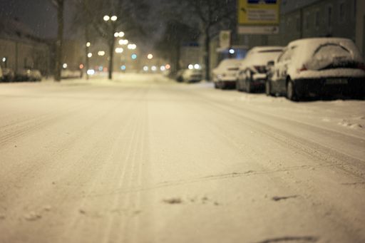 A blurry shot of cars parked along the street side covered with snow in winter
