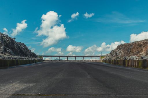 A stone-made bridge in an industrial area and an asphalt road under a beautiful cloudscape