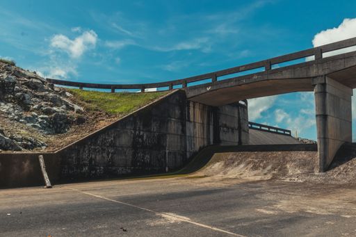 A stone-made bridge in an industrial area and an asphalt road under a beautiful cloudscape