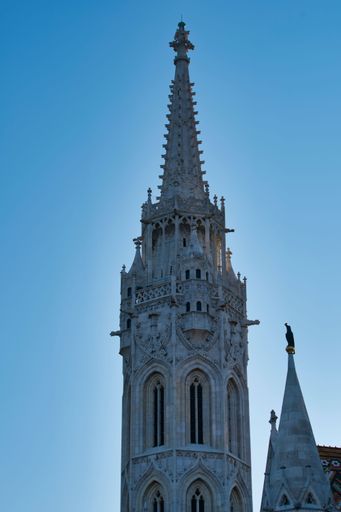 A vertical shot of the Matthias Church tower against a blue sky in Budapest, Hungary