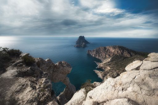 A beautiful scenery of the sea surrounded by rocky cliffs under a cloudy sky