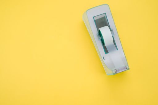 A top view of a sticky tape on a cutter isolated on a yellow background