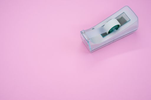 A top view of a sticky tape on a cutter isolated on a pink background