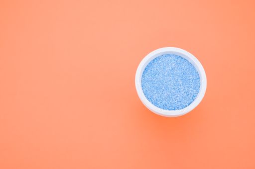 A top view of blue sand in a small cup isolated on an orange background