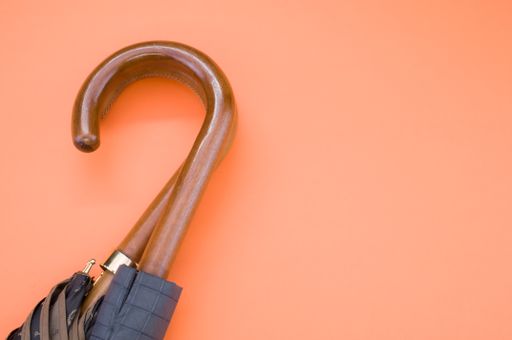 A top view of two umbrellas with wooden handles isolated on an orange background