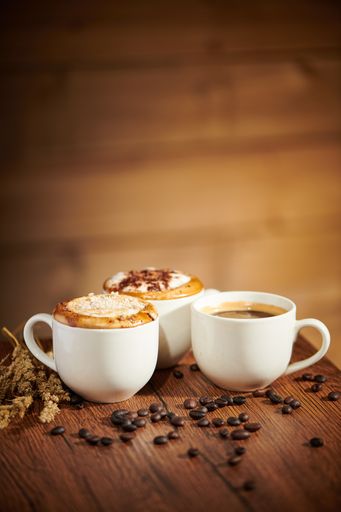 A vertical shot of cups of coffee on a wooden tab