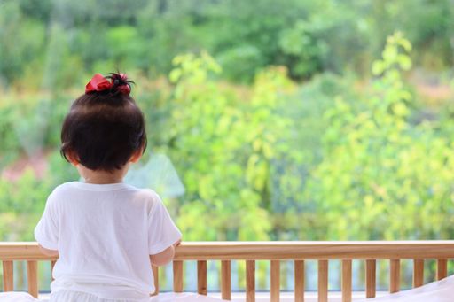 A shallow focus shot of a baby inside a crib and looking out the window