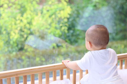 A shallow focus shot of a baby inside a crib and looking out the window