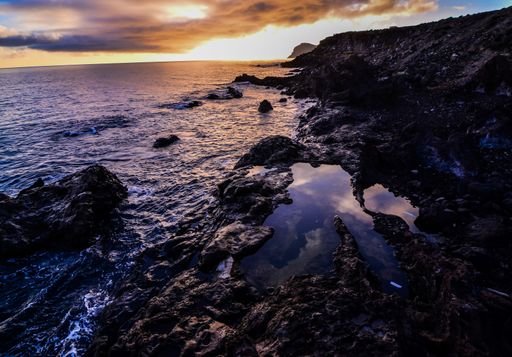 A high angle shot of rocky seashore with a sunrise in the sky