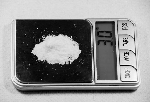 A closeup of a white powder weighed on a scale perfect for heroin and cocaine, drug concept