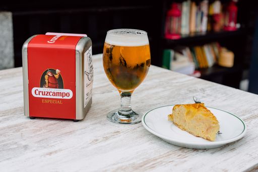 Cerveza Cruzcampo servida en una terraza junto a una tortilla.