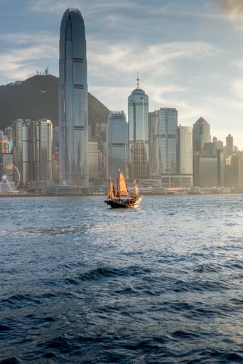 A vertical shot of skyscrapers in Hong Kong surrounded by water under the sunlight in China