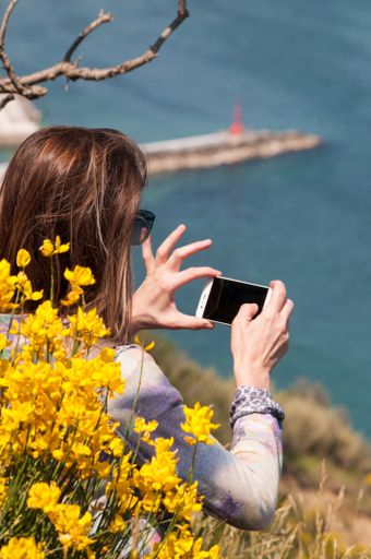 A vertical shot of a female taking the photo of the view at the Monte San Bartolo, Italy