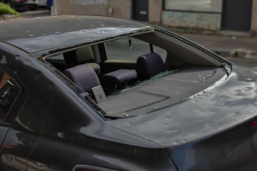 Hail damaged car with smashed rear window waiting repair at an auto panel garage.