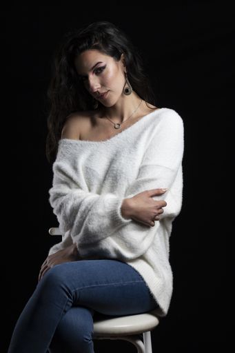 A vertical shot of a Hispanic female posing on black background
