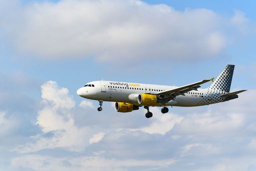 An aerial shot of a white and yellow tri copter airplane skying in a blue cloudy sky