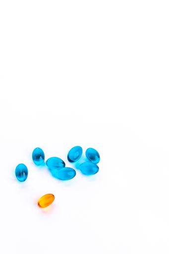 A vertical shot of yellow and blue vitamin capsules isolated in white background