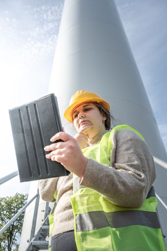 A female worker wearing a safety vest curiously looking at her tablet