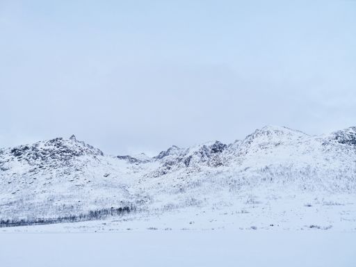 A low angle shot of snow-covered hills in Kvaloya island, Norway during winter