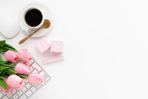 An overhead shot of a workspace desk on a white background - women's day concept