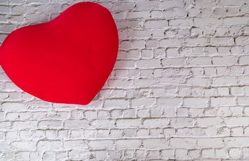 A top view of a red heart decoration on a white brick wall